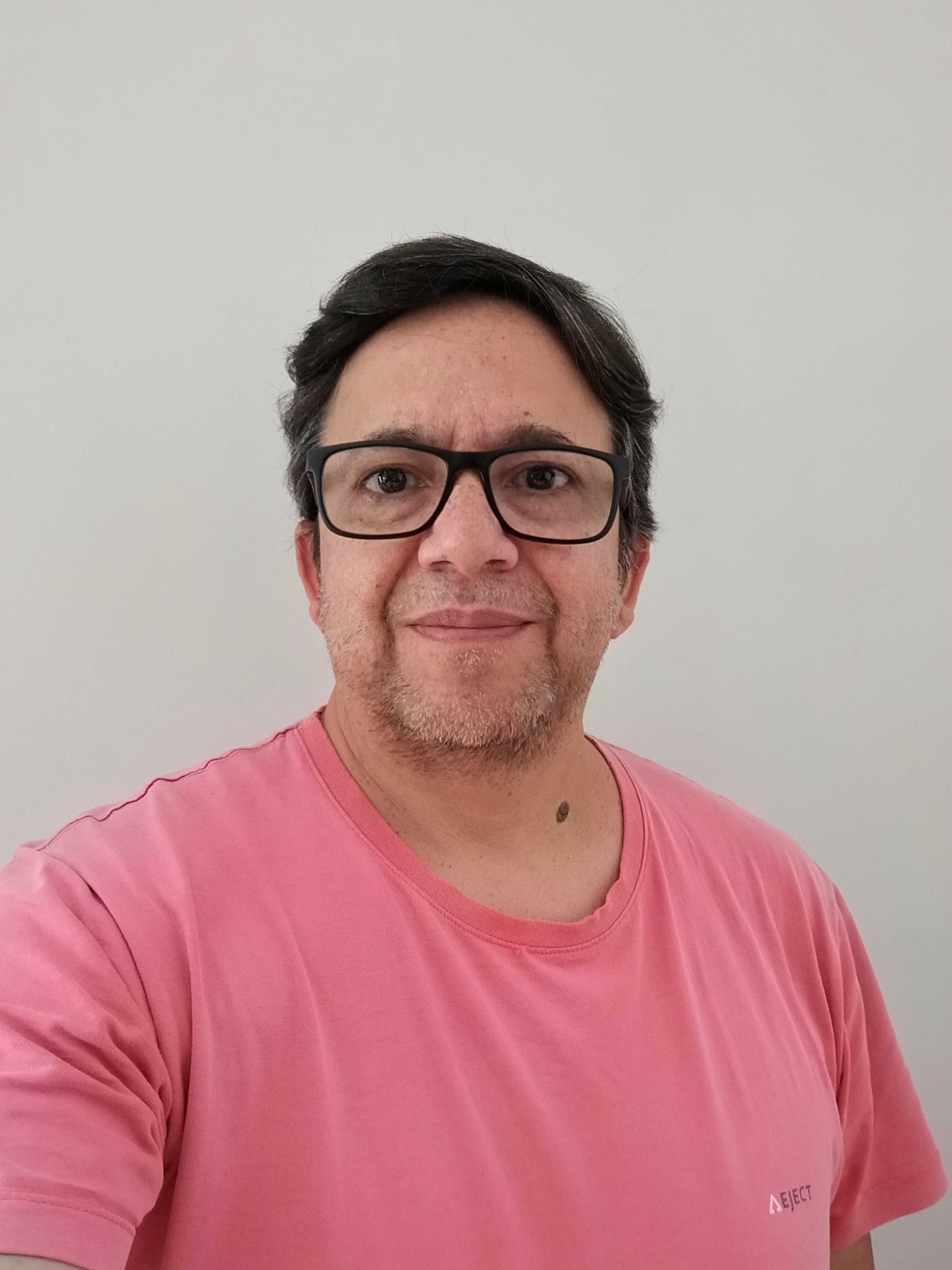 Marcello Emidio com camiseta rosa e sorriso discreto